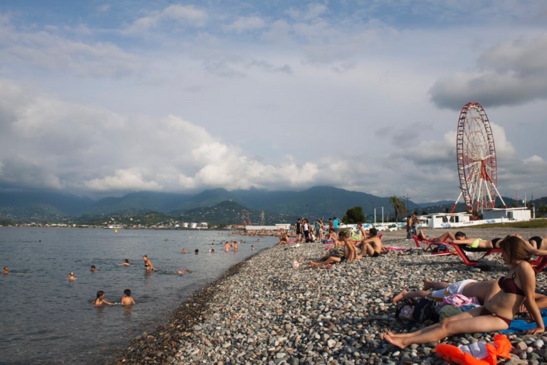 people laying on a beach near a Ferris wheel