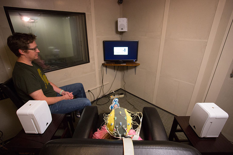 Communicative Sciences and Disorders professor looking at a monitor of an experiment