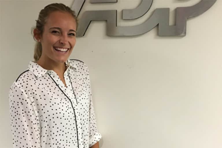 Katherine Harvey smiling as she stands next to the ADP sign.