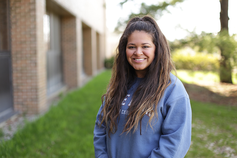 Graduating senior Sasha Zidar poses in front of ComArtSci.